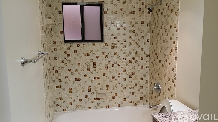 A white bathtub sits in a bathroom with a shower curtain and a window.