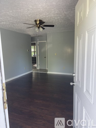 A room with a ceiling fan and wood flooring.