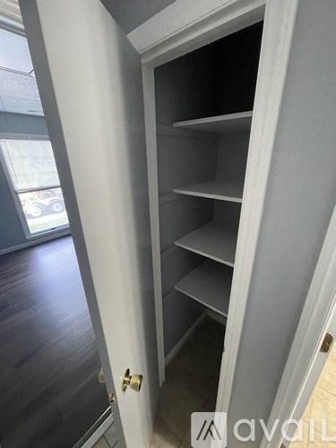 A white door with a gold handle is open to a dark interior.