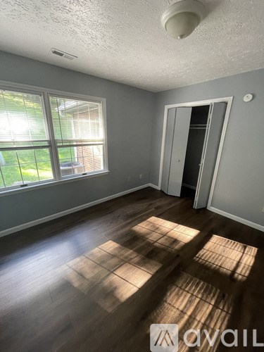 A room with wooden floors and a window letting in sunlight.