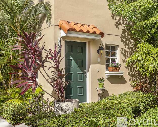 A house with a green door and a window with a plant on the ledge.