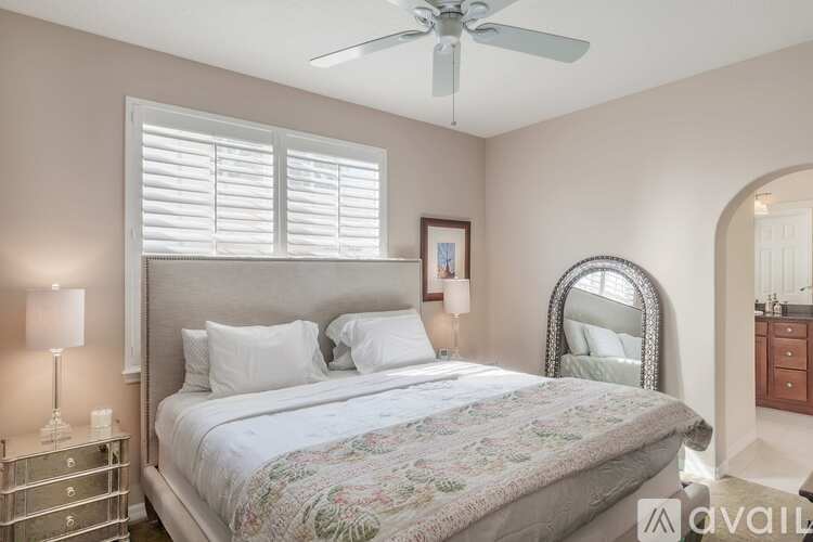 A bedroom with a large bed and a ceiling fan.