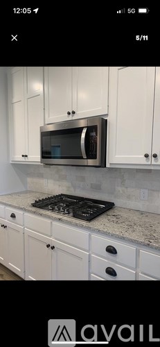 A kitchen with white cabinets and a black stove top.
