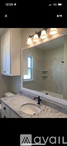 A bathroom with a granite countertop and a large mirror.