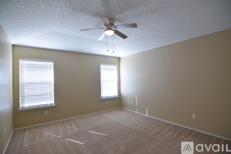 A room with a ceiling fan and two windows.