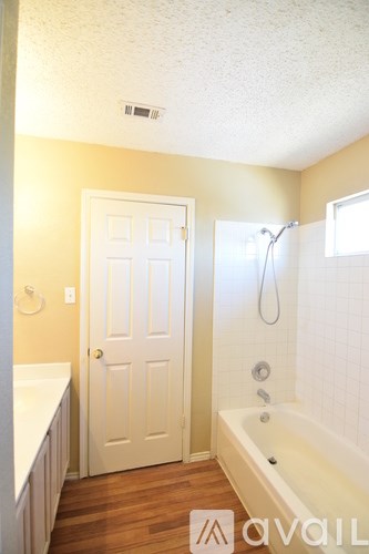 A bathroom with a white door and a bathtub.