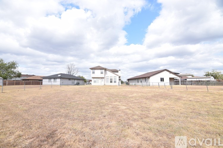 A large open field with a row of houses in the distance.