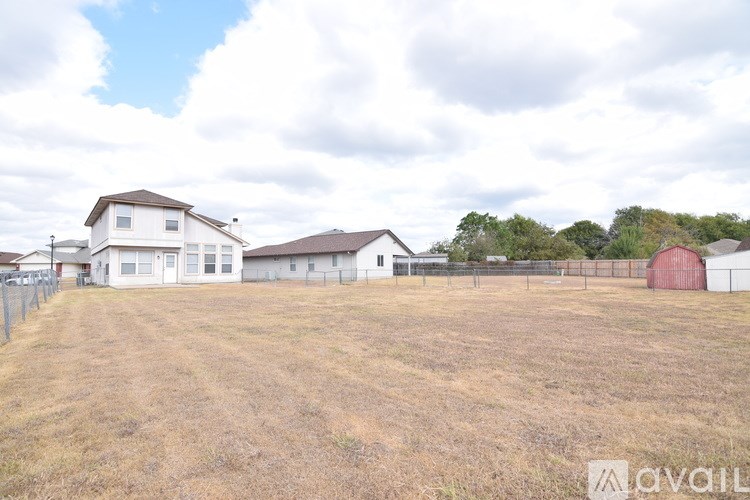 A field with a house and a barn in the background.