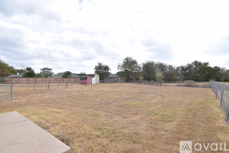 A grassy field with a fence and a building in the distance.