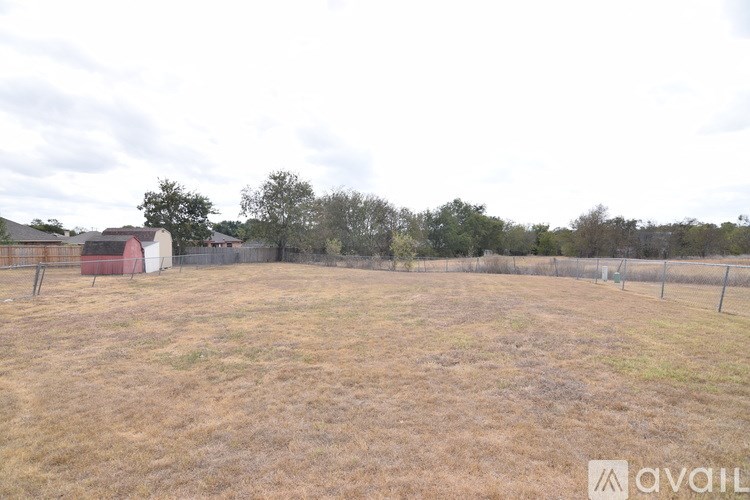 A field with a fence and a shed in the background.