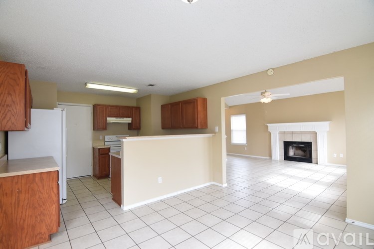 A spacious kitchen with a white tile floor and a fireplace in the living room.