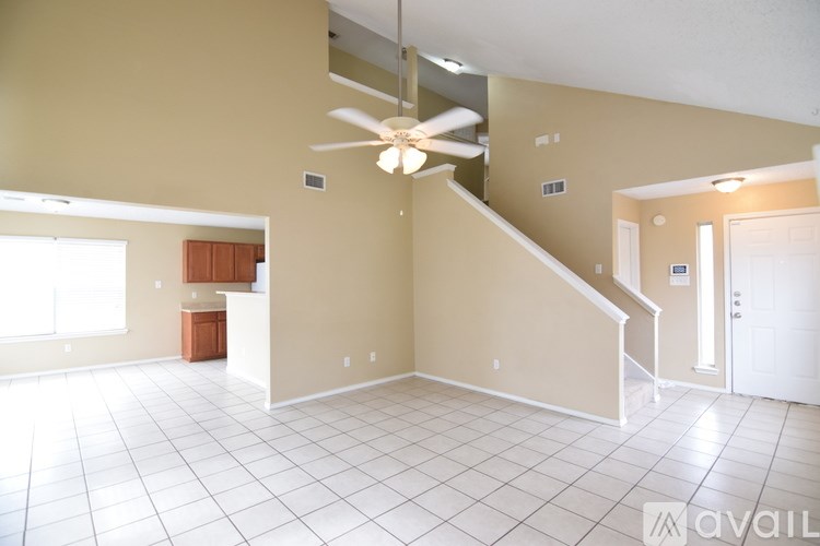 A spacious room with a staircase and a ceiling fan.