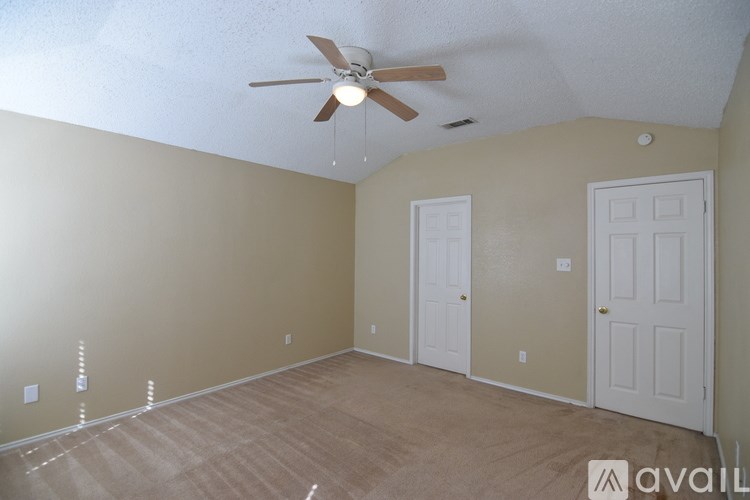 A room with a ceiling fan and two doors.