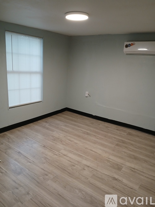 A room with wooden flooring and a window with blinds.