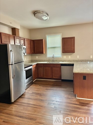 A kitchen with wooden floors and a stainless steel refrigerator.