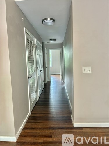 A long hallway with a light on the ceiling and a door at the end.
