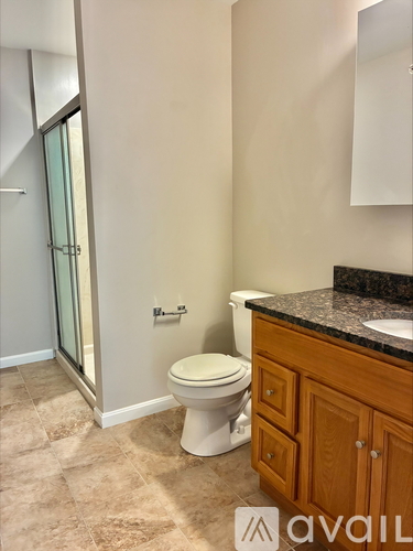 A bathroom with a toilet, sink, and a cabinet.