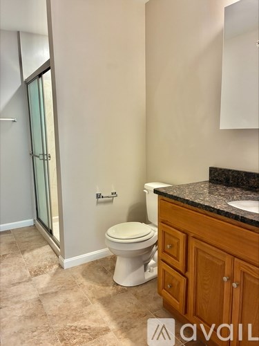 A bathroom with a toilet, sink, and a cabinet.