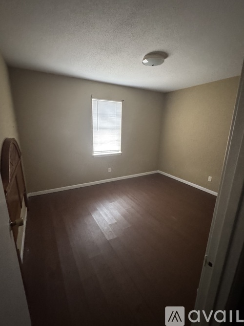A room with a window and wooden flooring.