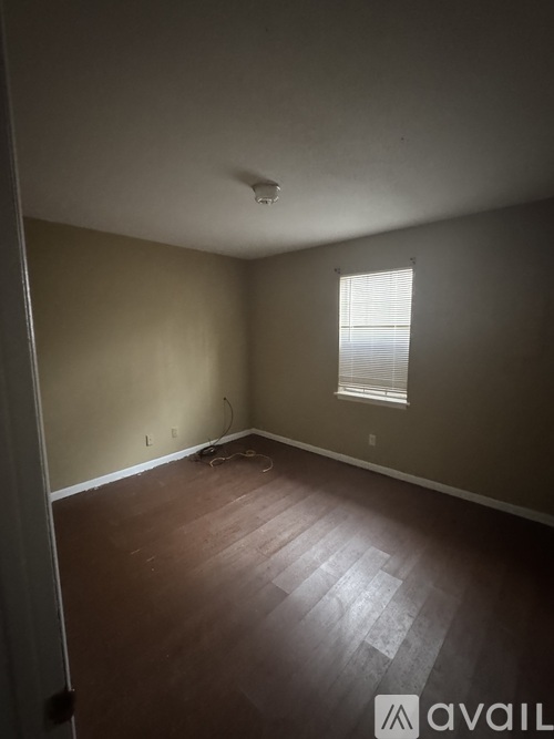 A room with wooden floors and a window with blinds.
