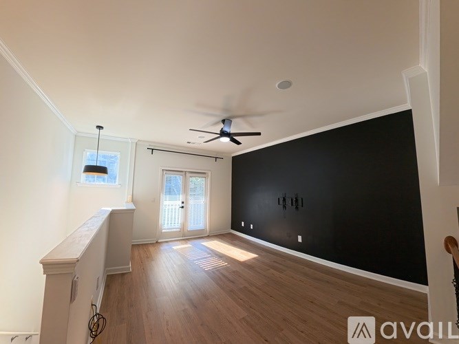 A room with a ceiling fan and a black wall.