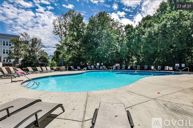 A swimming pool surrounded by trees and lounge chairs.