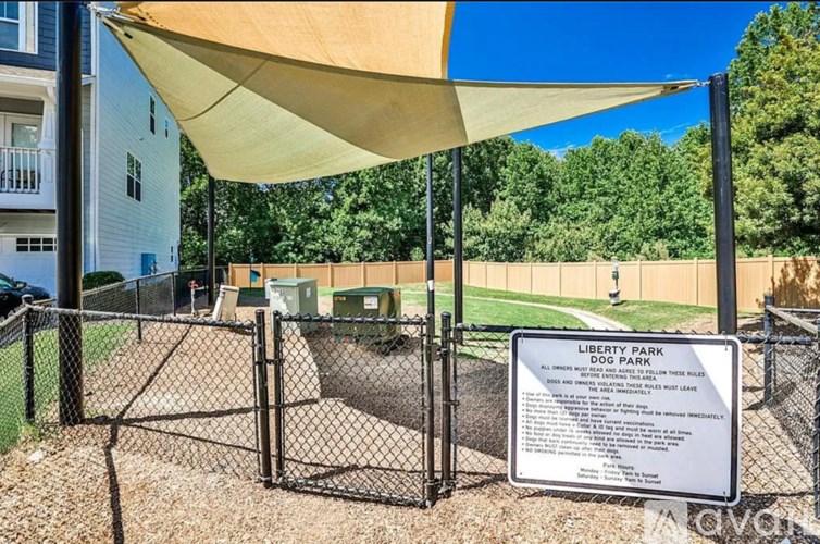 A dog park sign is posted under a canopy.