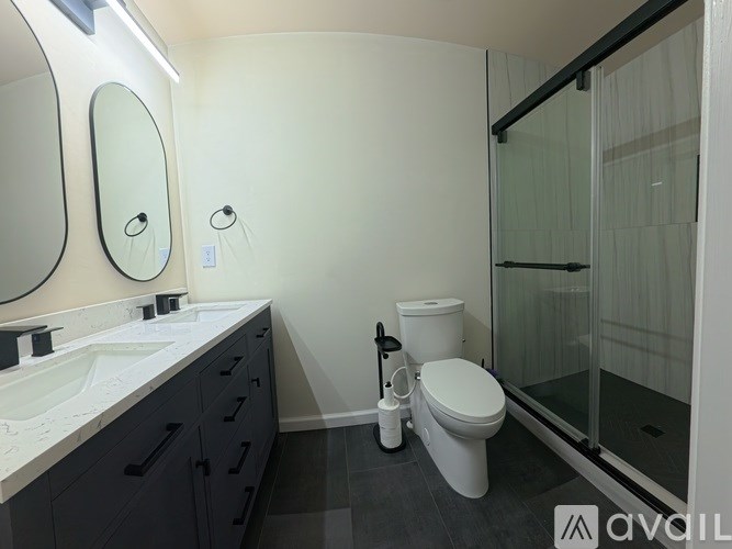 A bathroom with a toilet, sink, mirror, and shower.
