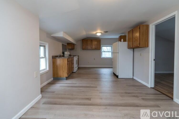A kitchen with wooden cabinets and a white refrigerator is available.