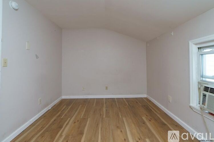 A room with wooden flooring and a window on the right side.