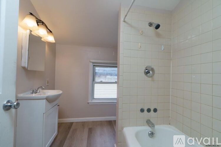 A bathroom with a white tub, sink, and a window.