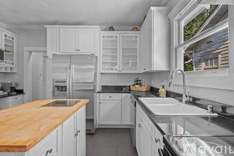A kitchen with white cabinets and a wooden countertop.