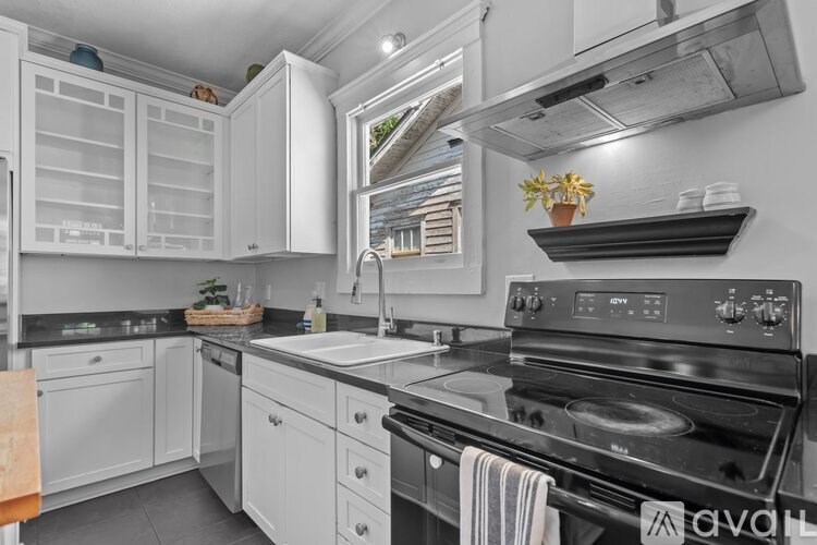 A kitchen with white cabinets and a black stove top oven.