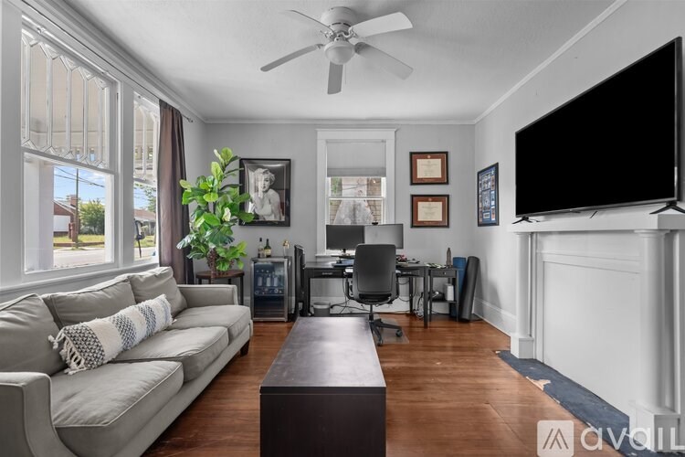 A living room with a couch, a television, and a desk.
