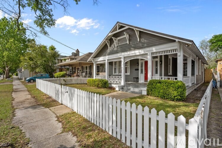 A white picket fence surrounds a two-story house.