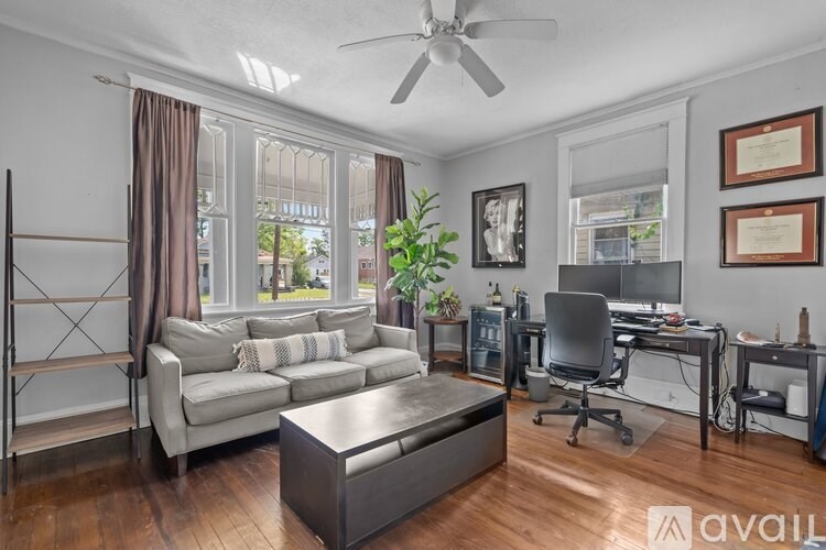 A living room with a grey couch, a brown coffee table, and a ceiling fan.