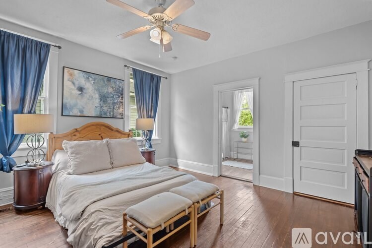 A bedroom with a bed, a bench, and a ceiling fan.