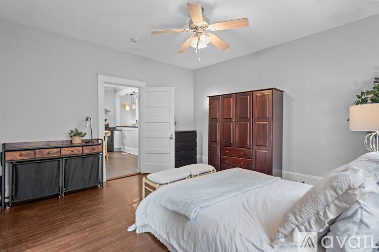 A bedroom with a bed, dresser, and a ceiling fan.