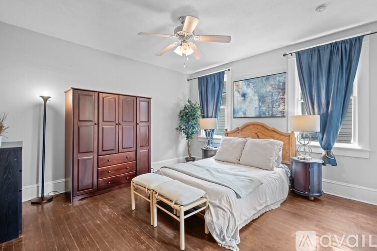 A bedroom with a bed, dresser, and ceiling fan.