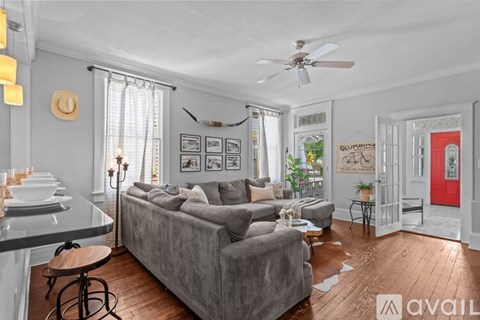 A living room with a grey couch and a red door.