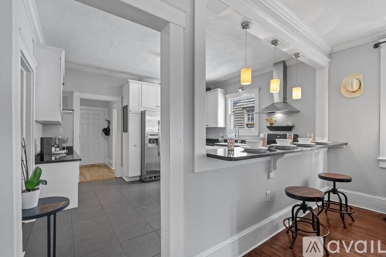 A kitchen with a bar stool and a table with a potted plant on it.