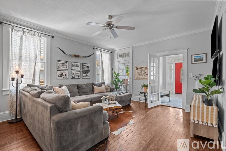 A living room with a grey couch and a fan on the ceiling.