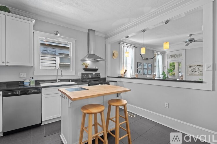 A kitchen with white cabinets and a wooden island.
