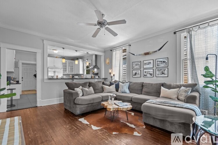 A living room with a grey couch, a coffee table, and a ceiling fan.