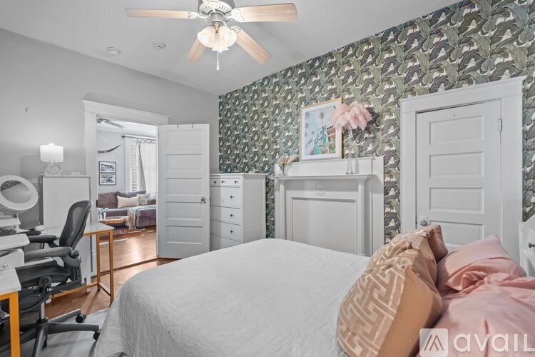 A bedroom with a patterned wallpaper and a bed with a white comforter.