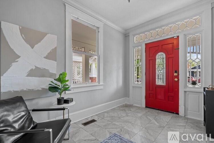 A room with a red door and a plant on a table.