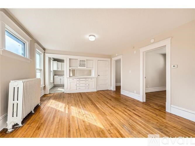 A spacious room with wooden floors and white walls.