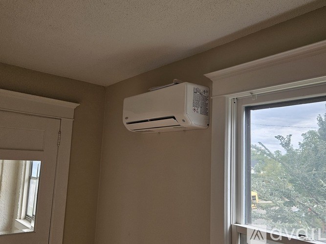 An air conditioner unit is mounted on a wall above a window.