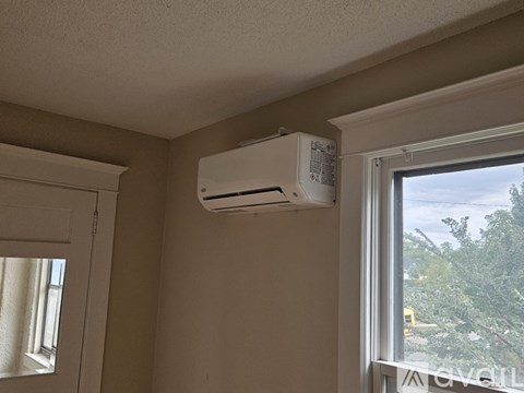 An air conditioner unit is mounted on a wall above a window.
