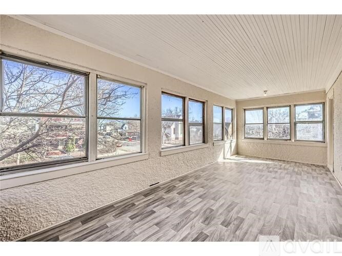 A spacious room with large windows and wooden flooring.